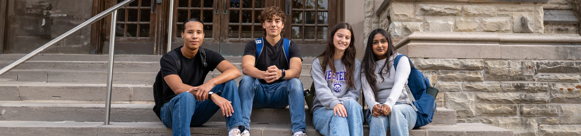 Four students sitting on the steps at Middlesex College.