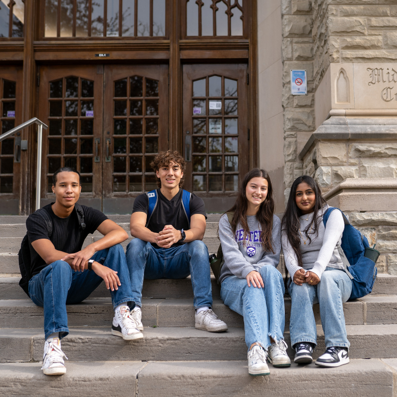 Four students sitting on the steps at Middlesex College.