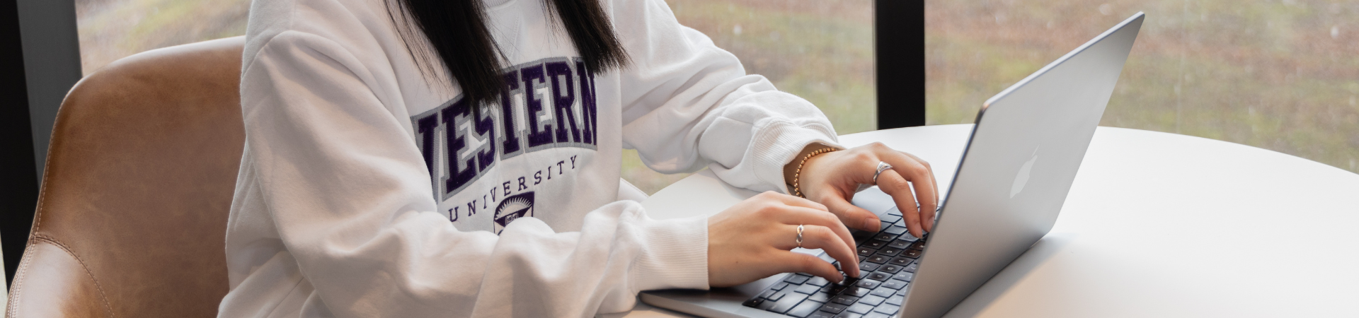 hands typing on a laptop.