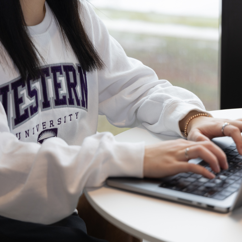 hands typing on a laptop.